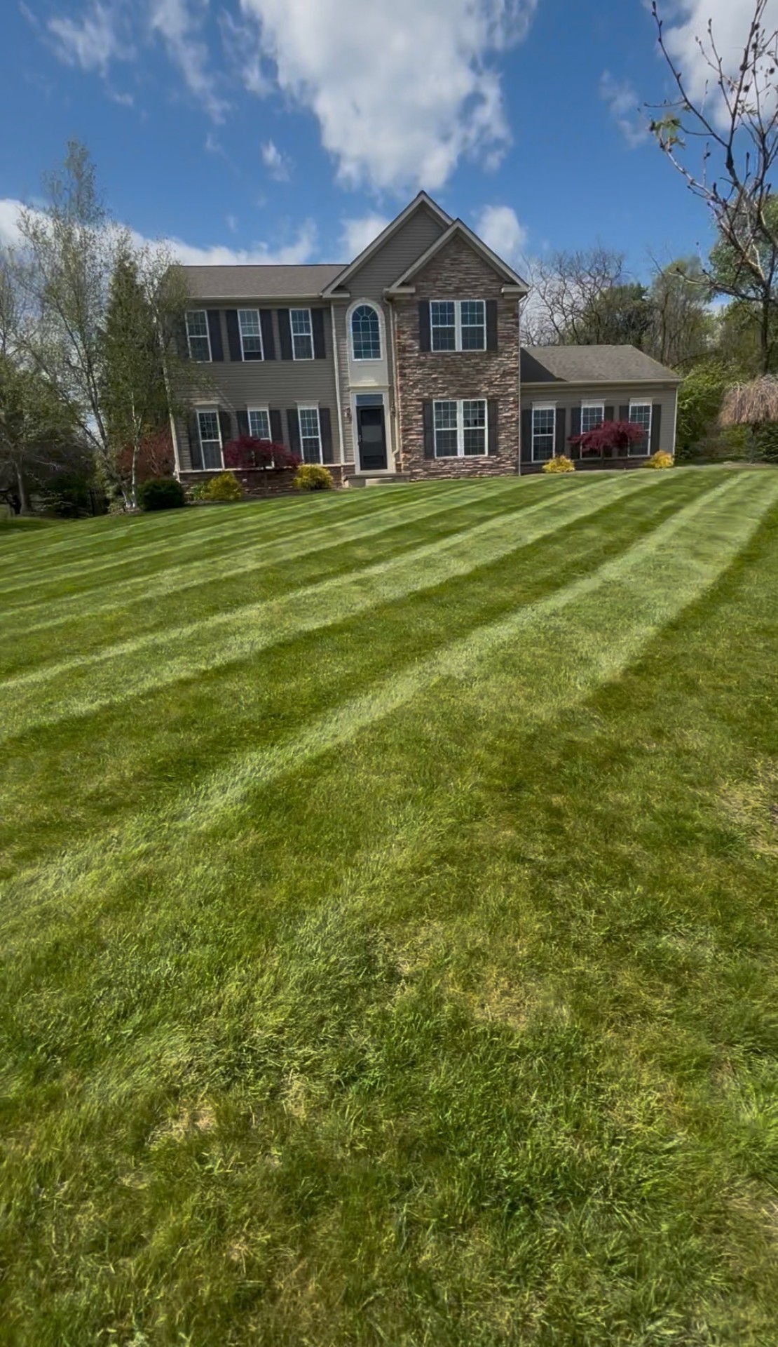 Freshly striped lawn in front of a stone-accented home