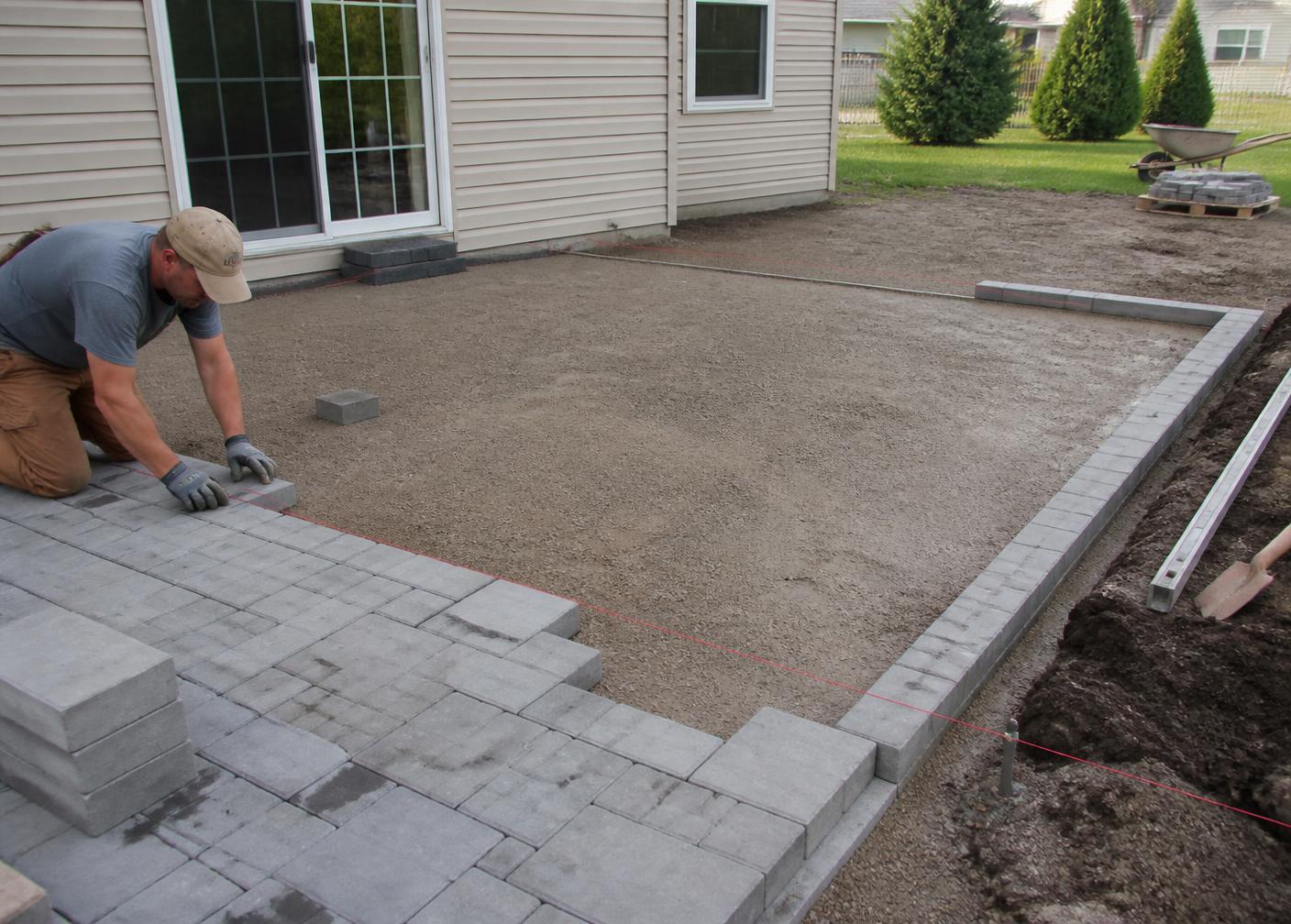 Paver patio installation in progress with compacted base and border course